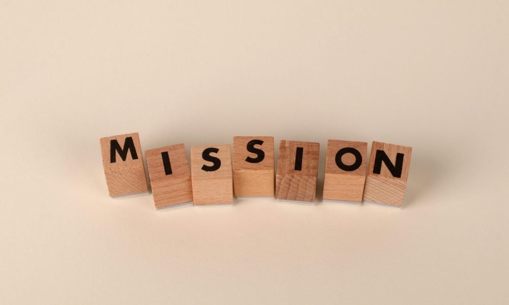 Wooden blocks with letters spelling 'MISSION' against a neutral beige backdrop.