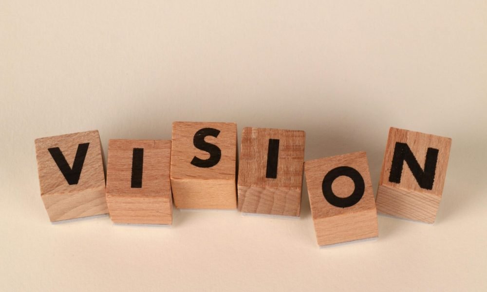 Wooden blocks spelling VISION on a beige background symbolizing clarity and foresight.